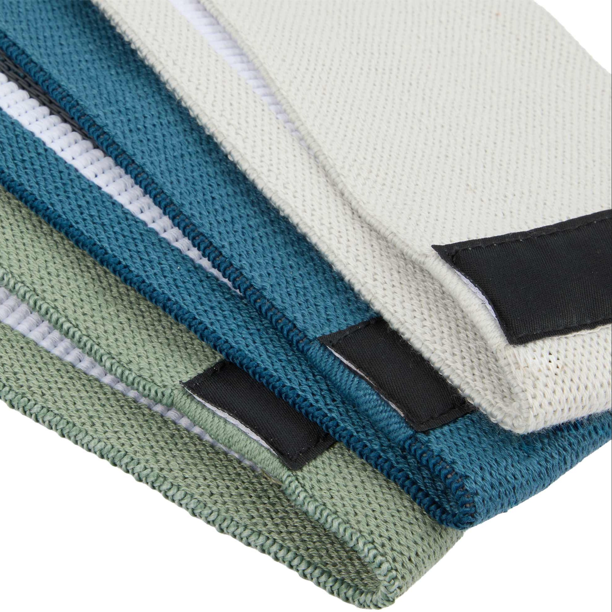 Close-up of resistance bands in green, blue, and white on a white background